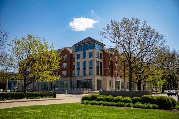 The Lewis Honors College on a sunny day in Lexington. Clear skies and very vibrant green grass.