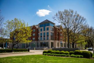 The Lewis Honors College on a sunny day in Lexington. Clear skies and very vibrant green grass.