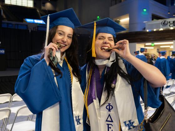 Students biting the Honors medallion