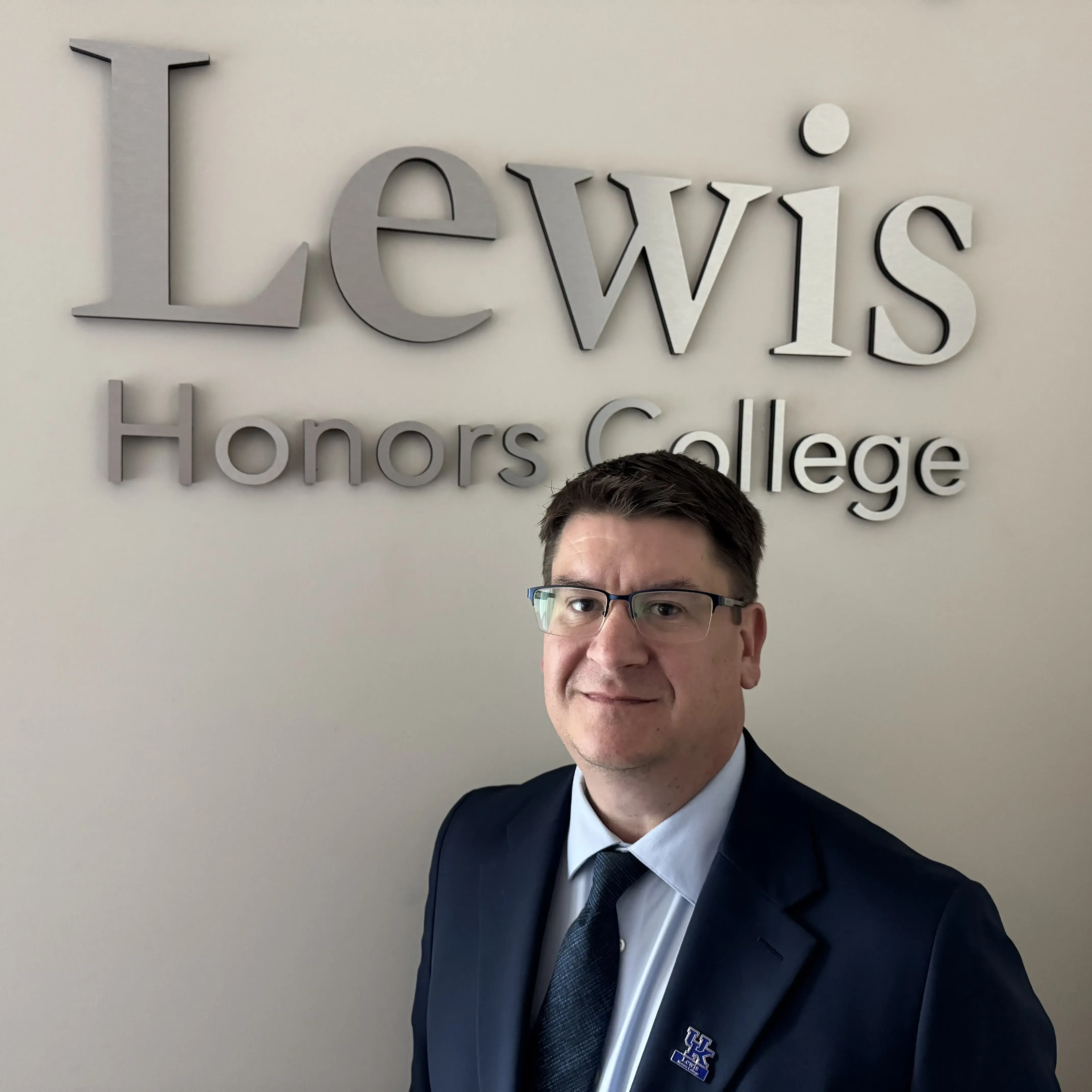 Jim Buss standing in front of Lewis Honors College sign